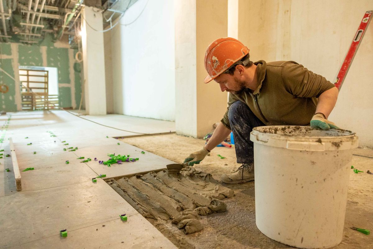Handyman laying floor tiles during a renovation project